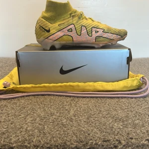 Gula Nike air zoom mercurial 15 elite fg Fotbollskor - Snygga gula Nike air zoom mercurial 15 elite fg Fotbollskor med snörning.Skorna har en strumpliknande passform och en iögonfallande design med stora 'AIR'-bokstäver på sidan. Perfekta för fotbollsplanen med sina greppvänliga dobbar. Mitt pris 299nytt pris 3299kr. Skriv vid minsta fråga 😁 kan gå ner vid snabb affär 🕰️