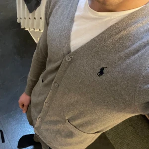 Grå Ralph Lauren Kofta / Cardigan - Säljer en stilren grå kofta från Ralph Lauren i mycket bra skick. Koftan är liten i storlek så står M på den, men den sitter som en S. Hör av dig om du har några frågor