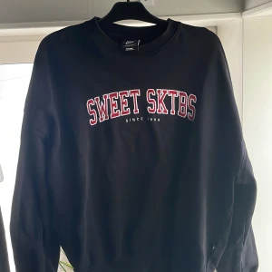 Svart sweatshirt från Sweet SKTBS.   - Säljer en svart sweatshirt från Sweet SKTBS med tryck i vitt och rött på bröstet. Tröjan är i mycket bra skick och perfekt för både vardag och chill. Den har en klassisk passform och är superbekväm. Nypris ca 800