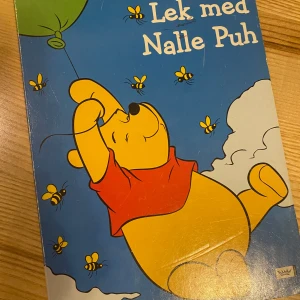 Lek med Nalle Puh - En färgglad och rolig bok där Nalle Puh och hans vänner hittar på äventyr i Sjumilaskogen. Boken är fylld med aktiviteter och gömda överraskningar på varje sida. Perfekt för barn som älskar att utforska och leka med Puh, Nasse, Tiger och de andra karaktärerna.