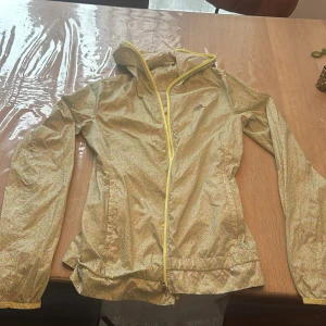 Mönstrad vindjacka från Adidas - Säljer en supercool vindjacka från Adidas i ett unikt mönster med ljusa färger. Jackan har en dragkedja framtill och är perfekt för vår och sommar. Den är i bra skick och har långa ärmar. Perfekt för träning eller en promenad i stan!