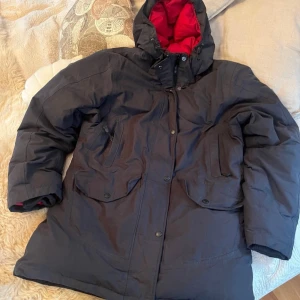Svart dunjacka från Henri Lloyd - Säljer en svart dunjacka från Henri Lloyd i mycket bra skick. Jackan har är perfekt för vintern. Den är vindtät, vattentät och andas bra. Utrustad med dragkedja och knappar för extra skydd. Stor och mysig huva för kalla dagar.