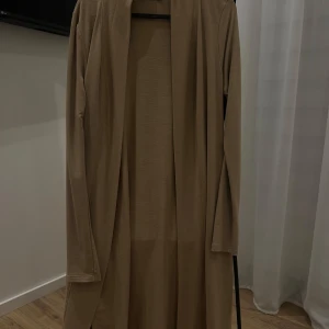 Beige lång kofta - Snygg beige lång kofta med långärmad design. Perfekt för höst och vår, med en stilren och enkel look. Från BikBok. 