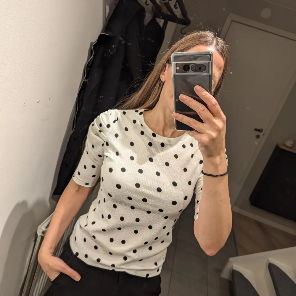 Säljer en superfin vit topp med svarta prickar från Lindex. Den har trekvartsärm och en snygg rynkdetalj på axlarna.. Yläosat.