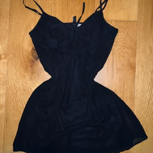 Svart klänning - Snygg svart klänning med smala axelband och en söt rosett framtill. Perfekt för en utekväll eller fest. Knappt använd 