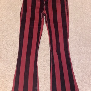 Svart/röd randiga Gothicana jeans - Svart/röd randiga Gothicana jeans med utsvängda byxben.