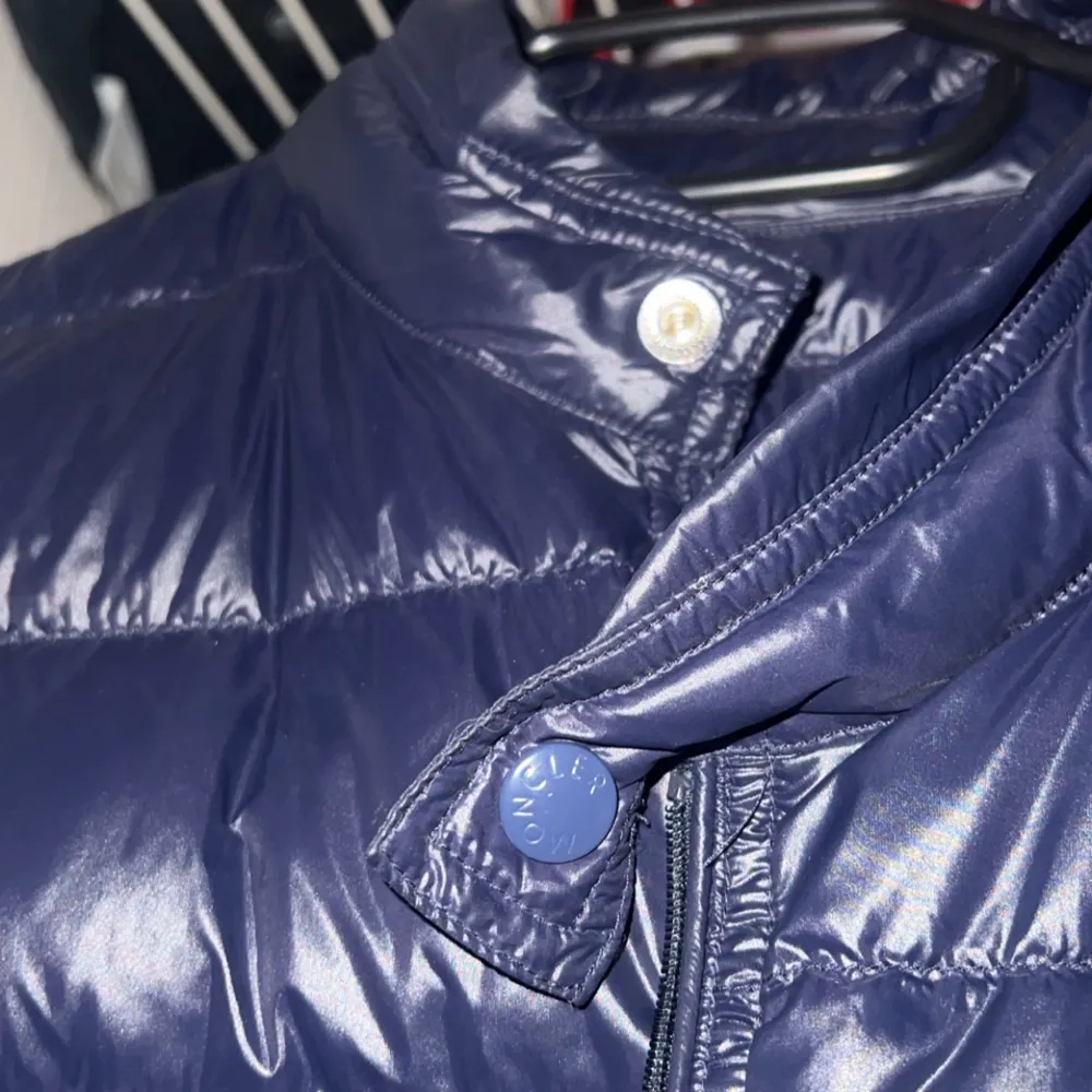 Snygg mörkblå dunväst från Moncler med dragkedja och knappar. Västen har en quiltad design och Moncler-logga på bröstet. Perfekt för kyligare dagar och en perfekt julklapp till dig som vill gå med stil. Västen är i storlek S. Takit.