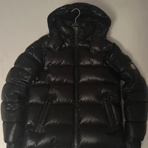 Moncler Maya - Säljer en snygg svart dunjacka från Moncler, jackan är köpt i November 2024 så den är alldeles ny i perfekt skick. Har kvitton och allting kvar säljer den pga jag fick den i present men har redan en likadan mörkblå. Jackan är i storlek 1 som represternar storlek S/M, det är bara att höra av sig vid funderingar. Pris kanske kan sänkas lite vid snabb affär.