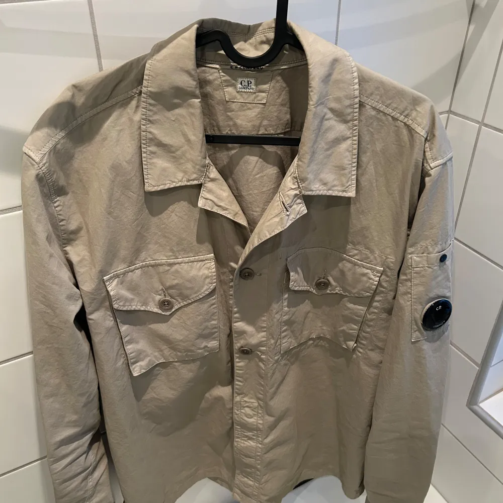 Säljer en snygg beige overshirt från CP Company i storlek XL men som även passar L. Den är endast använd ett fåtal gånger och inga defekter!. Skjortor.