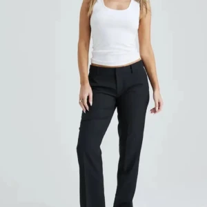 Svarta kostymbyxor med slits  - Snygga svarta kostymbyxor med en klassisk design. Byxorna har en rak passform och är låg midjade med slits  , vilket ger en stilren look. Perfekta för en chic och professionell stil.