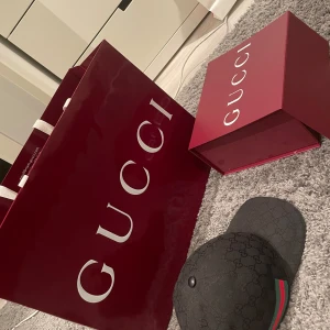 Svart keps från Gucci - Säljer en snygg svart keps från Gucci i storlek L. Kepsen har det klassiska Gucci-mönstret och en justerbar rem baktill. Köptes på Gucci butiken i Stockholm nypris 4600. Kommer med originalförpackning och påse.