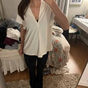 Vit v-ringad blus - Säljer en stilren vit blus med v-ringning och korta ärmar. Perfekt för en avslappnad men ändå elegant look. Passar bra till både jeans och kjol.