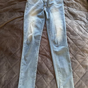 Levi's Revel Skinny Jeans 26 - Snygga Levi's Revel jeans i en klassisk blå tvätt. Dessa skinny jeans har en demi curve passform som framhäver figuren. Perfekta för en stilren look med den ikoniska Levi's loggan på bakfickan.