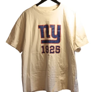 Beige t-shirt från H&M med NFL-tryck - Säljer en beige t-shirt från H&M med ett coolt NFL-tryck i blått och rött på framsidan. T-shirten har korta ärmar och är tillverkad i bomull, vilket gör den bekväm att bära. 