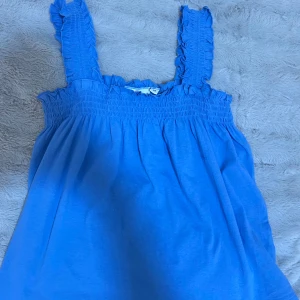 Blå topp från Kappahl - Söt blå topp från Kappahl med volangdetaljer på axelbanden. Har använt bara 1 gång och den är för liten för mig så vill gärna sälja den🤍och pris kan diskuteras 