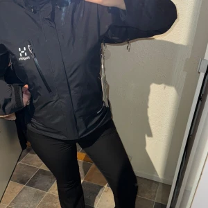 Svart Astral jacka från Haglöfs - Säljer en svart Haglöfs jacka i Gore-Tex-material. Jackan har en praktisk dragkedja och flera fickor, perfekt för utomhusaktiviteter. Den är långärmad och har en justerbar huva för extra skydd mot väder och vind. Helt ny aldrig använd. Prislapp sitter kvar. Pris går att diskutera!!