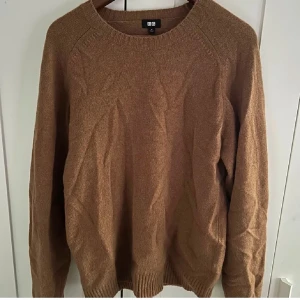  Uniqlo Ulltröja  - Säljer en stilren brun tröja från Uniqlo. Perfekt för kyligare dagar med sin mjuka och bekväma passform. Tröjan har långa ärmar och en rund halsringning.