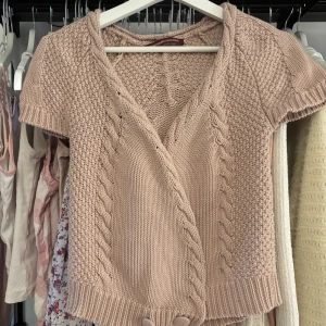 Rosa stickad kofta från Comptoir des Cotonniers - Säljer en söt rosa stickad kofta från Comptoir des Cotonniers. Koftan har korta ärmar och ett flätat mönster framtill. (Brukar ha en safety pin så den sitter bättre) Den är v-ringad och har dekorativa knappar vid nederkanten.  öppen för prisförslag 🩰🌸 nypris 85€ 