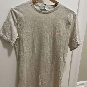 Beige t-shirt från Les Deux - Säljer en beige t-shirt från Les Deux med en liten broderad logga på bröstet. Den är i mycket bra skick men tyvärr för liten...pris kan diskuteras