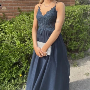 Mörkblå balklänning från JJ's House - Superfin mörkblå balklänning med spetsdetaljer och snörning i ryggen. Klänningen har en vacker, flödande kjol och är perfekt till balen. Klänningen är köpt från JJ’s House och jag har endast haft den till min bal
