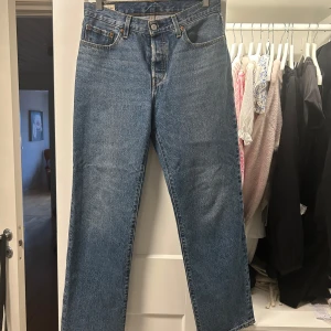 Blå jeans från Levis - Säljer ett par klassiska blå Levis jeans i modell 501. De har en rak passform och är högmidjade med fem fickor och knappgylf. Endast lite tecken på användning nere vid foten 