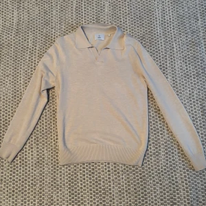 Beige pikétröja från Bläck - Snygg beige pikétröja från Bläck i storlek S. Tröjan har långa ärmar och en klassisk krage. Perfekt för en stilren look.