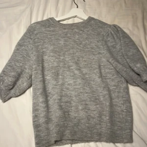 Grå stickad tröja från Gina Tricot - Mysig grå stickad tröja från Gina Tricot i storlek XS. Perfekt för kyliga dagar med sin mjuka och bekväma passform. Tröjan har långa ärmar och en klassisk rund halsringning.