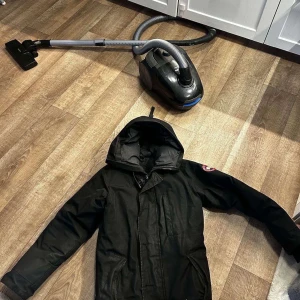 Svart dunjacka från Canada Goose - Säljer en svart dunjacka från Canada Goose storlek S men är stor i storlek. Slitage här och där det matta tygen har blivit glansigt. Tänk dig som en ny bil rätt med tiden blir den glansig. Flitigt använd därav priset.