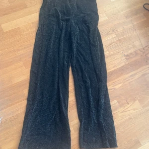 Svarta glittriga byxor från Esmara - Snygga svarta byxor från Esmara med glittrig effekt. Byxorna har en wide leg-stil som ger en trendig look. Perfekta för att sticka ut med stil.