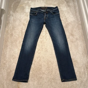 Blå jeans från Jacob Cohen - Snygga blå jeans från Jacob Cohen, tillverkade i Italien. De har en klassisk straight passform och är perfekta för en stilren look. Jeansen har en knappgylf och femficksdesign.