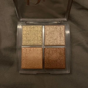 Ögonskuggspalett från Dior - Elegant ögonskuggspalett från Dior med fyra skimrande nyanser. Färgerna inkluderar en ljus guld, en champagne, en mjuk koppar och en djupare brons. Perfekt för att skapa både subtila och dramatiska looker.
