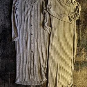 Grå ribbad långklänning - Två stilrena grå ribbade långklänningar/cardigan med v-ringning och knappar framtill. Perfekta för en avslappnad och elegant look.