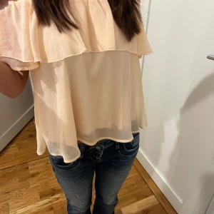 Beige/rosa offshoulder blus - Säljer en söt beige/rosa offshoulder blus med volangdetaljer 