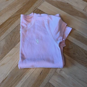 Rosa t-shirt från Polo Ralph Lauren - Säljer en söt rosa t-shirt från Polo Ralph Lauren med korta ärmar och en liten broderad logga på bröstet. 