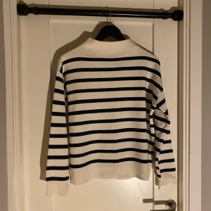 Randig tröja från Åhléns - Säljer en stilren randig tröja från Åhléns i storlek S. Tröjan är vit med svarta ränder och har långa ärmar. Perfekt för en avslappnad och klassisk look.