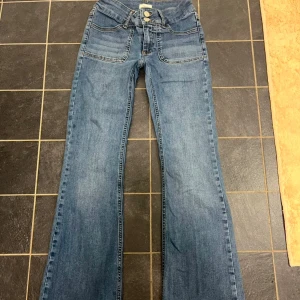Blå jeans från Nelly - Snygga blå jeans från Nelly med bootcut-stil. Knappfickor på baken och jeansen är i mycket bra skick! Perfekta för en avslappnad look.
