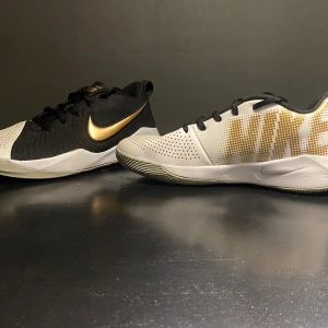 Nike sneakers i svart och vitt med gulddetaljer - Snygga Nike sneakers i svart och vitt med en iögonfallande guldfärgad swoosh. Skorna har en modern design med perforerade detaljer och snörning för en bekväm passform.