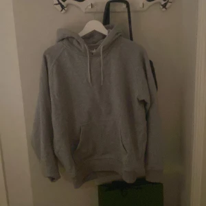 Grå hoodie från Urban Classics - Säljer en grå hoodie från Urban Classics. Den har en klassisk design med dragsko i huvan och en stor ficka framtill. Perfekt för en avslappnad stil.