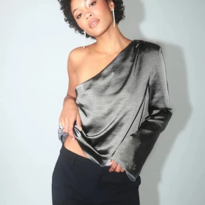 Grå oneshoulder topp - Snygg grå oneshoulder topp med en elegant och modern design. Perfekt till nyår. Passar bra till både jeans och kjol. Endast använd en gång. Kan gå ner i pris vid snabb affär!💓