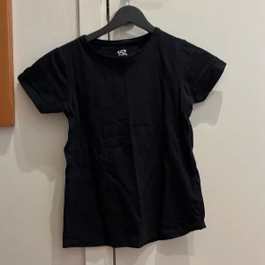 Svart t-shirt från Lager 157 - Säljer en klassisk svart t-shirt från Lager 157 i storlek 140 cl. T-shirten är tillverkad av 95% bomull och 5% elastan, vilket ger en skön och stretchig passform. Perfekt basplagg för alla tillfällen!