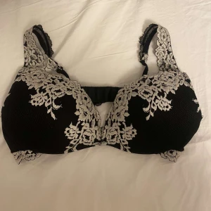 Intimissi bh - svart bh med vacker vit spetsdetaljering. Den har breda axelband och en bekväm passform. Perfekt för att känna sig både bekväm och stilfull. Storlek 85B