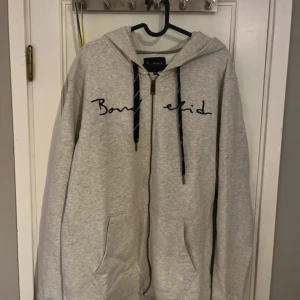 Grå hoodie från Bondelid - Säljer en grå hoodie från Bondelid med dragkedja och justerbar huva. Den har ett broderat Bondelid-tryck på bröstet och mörka snören. Perfekt för en avslappnad stil. Aldrig använd. 10/10.