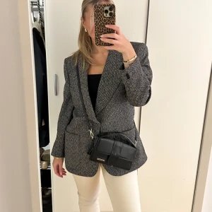 Svartvit kavaj - Snygg svartvit kavaj med klassisk passform och knappar framtill. Perfekt för en stilren look, oavsett tillfälle. Passar bra över en enkel topp eller skjorta.