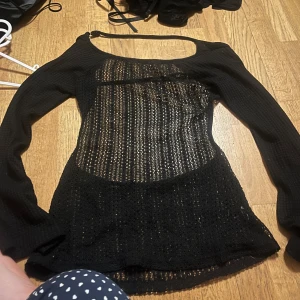 Svart stickad tröja - Snygg svart stickad tröja med långärmad design och ett transparent mönster. Perfekt för lager-på-lager-stil eller som statement-plagg. Rund halsringning och bekväm passform.