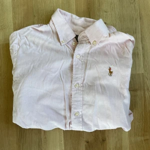 Polo Ralph Lauren Skjorta - Säljer nu en riktigt schysst ljus rosa Polo Ralph Lauren Skjorta, skicket är i 7/10! Hör av er om ni har några funderingar.