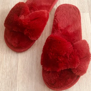 Röda fluffiga tofflor - Säljer ett par supermysiga röda tofflor med fluffig yta. Perfekta för att hålla fötterna varma och bekväma hemma. oanvända