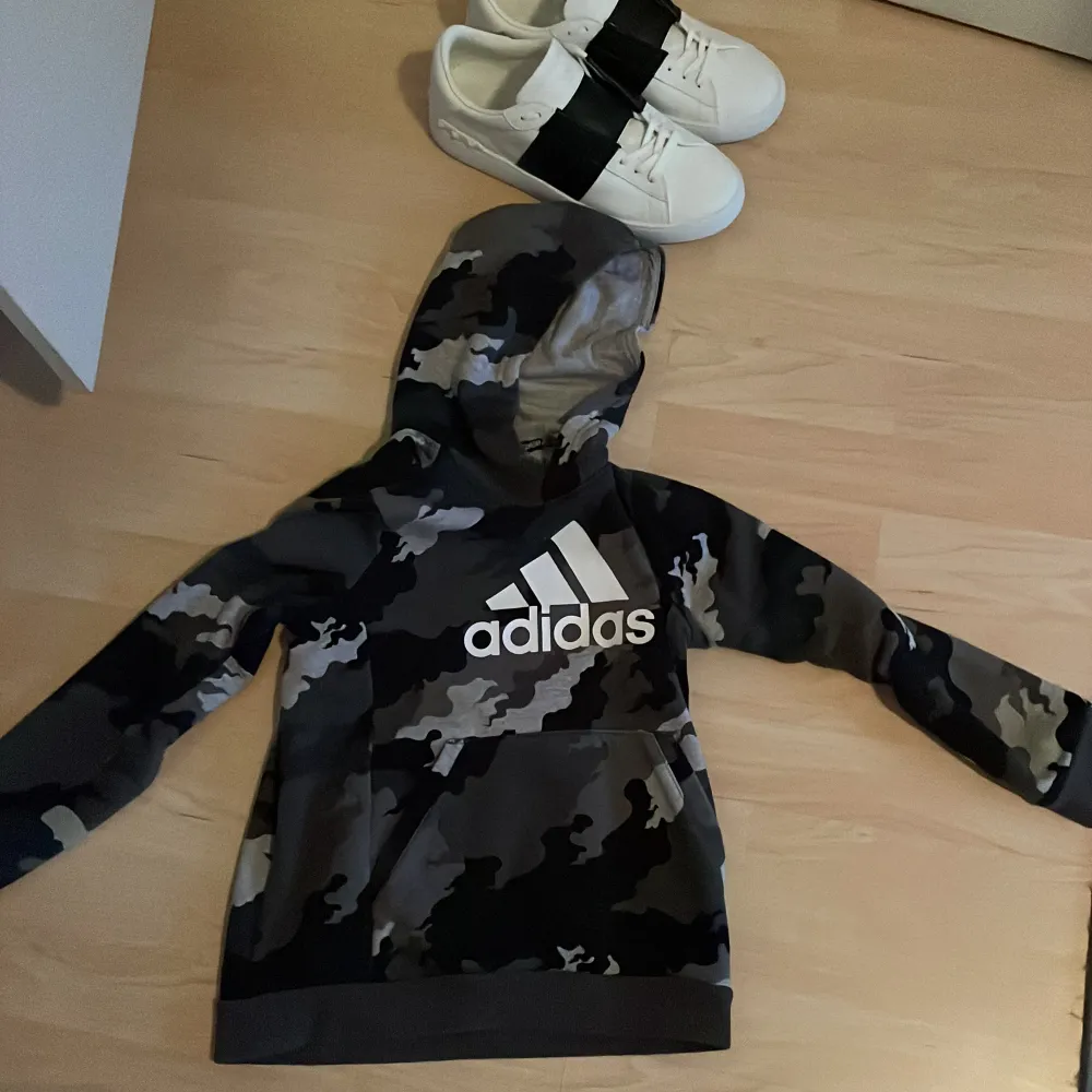 Tja säljer en camouflage adidas hoodie med en stor logga på framsidan. Tröja är använd men ändå fint skick inga större defekter eller hål. Storlek 140 men skulle mer säga 152. Hör av er vid minsta fundering! . Hoodies.