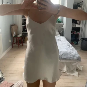 Satinklänning - Säljer denna vackra satinklänningen då den inte kommer till användning. Den är champagne färgad. Sparsamt använd, i bra skick. Perfekt för fest eller middagar m.m. Nypris 359kr.