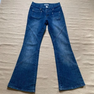 Blå jeans med vida ben från Miss Sixty - Säljer ett par snygga blå jeans med  bootcut och låg midja. De har coola detaljer som stora fickor bak och en knapp med logga framtill. Perfekta för en retro look! Fint skick!