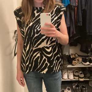 Topp - Zebra färgad topp med axelvaddar. 40 maskintvätt 99 % polyester 1% Elastan 